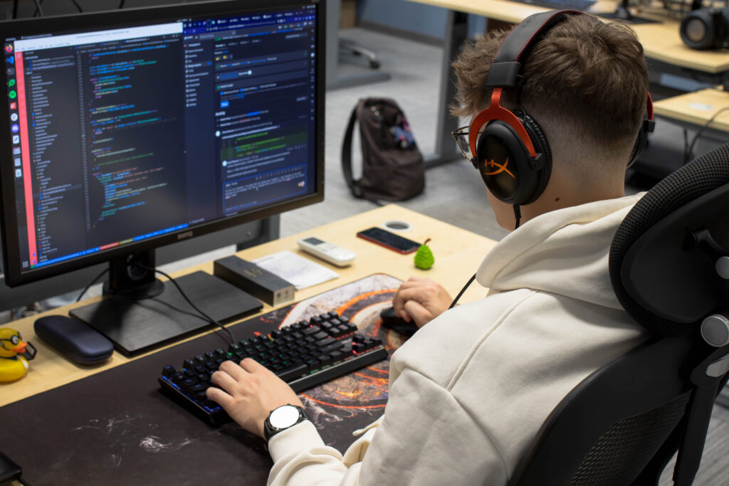 Deweloper z BlueRider.Software w słuchawkach, skupiony na pisaniu kodu na monitorze, co symbolizuje koncentrację w procesie tworzenia oprogramowania.